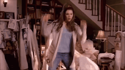 a woman is dancing in a living room in front of stairs .
