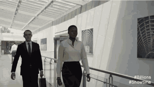 a man and a woman are walking down a hallway with the hashtag # billions showtime