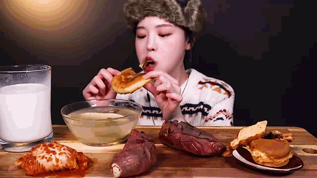 a woman is eating a slice of pizza next to a bowl of soup and a glass of milk