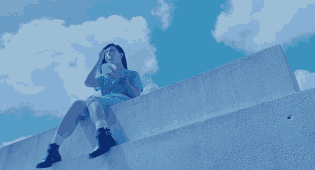 a woman sits on a ledge looking up at the sky