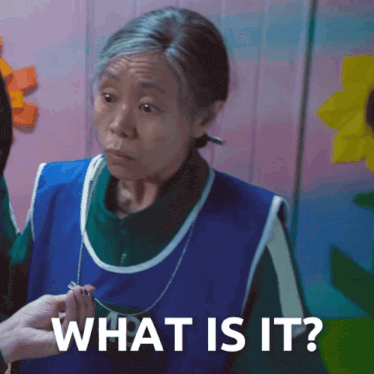 a woman in a blue apron is holding a necklace and asking what is it