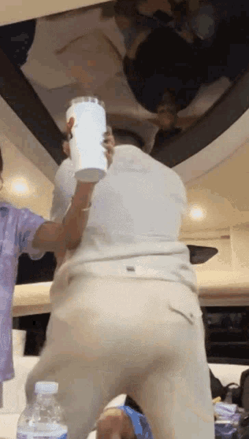 a man in a white shirt is holding a white cup with a mcdonald 's logo on it