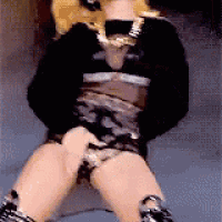 a doll is sitting on a table with her legs crossed and her hands on her hips .