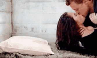 a man and a woman are kissing while laying on a bed .