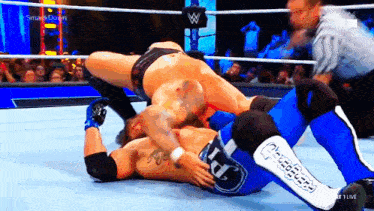 two men are wrestling in a wrestling ring with a referee .