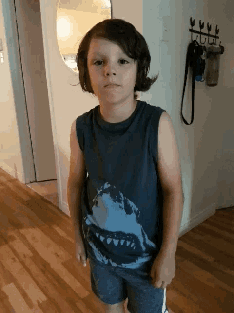 a young boy wearing a shark tank top and shorts