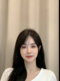 a young woman with long black hair is standing in front of a curtain and smiling .