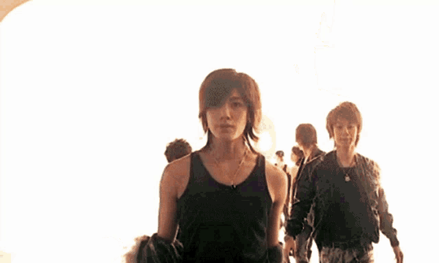 a man wearing a black tank top and a gold necklace