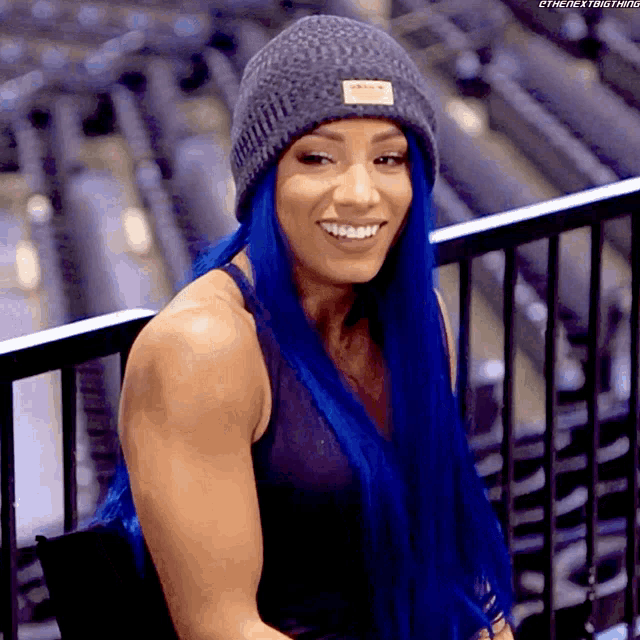 a woman with blue hair is wearing a gray beanie