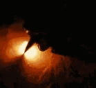 a close up of a person 's face in a dark room with a fire coming out of it .