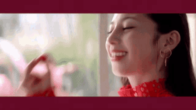 a close up of a woman 's face with her eyes closed and a red dress on .