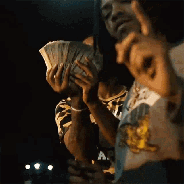 a man holding a stack of money in front of his face .