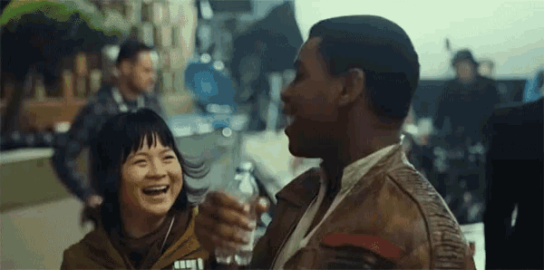 a man and a woman are laughing together while holding a drink .