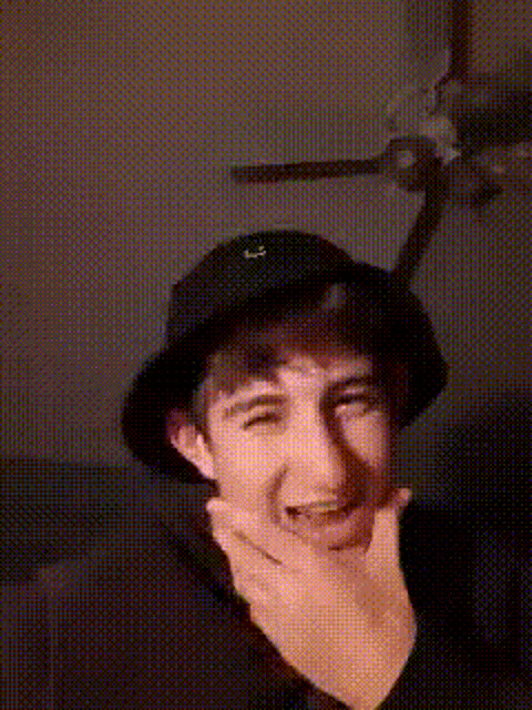 a young man wearing a black hat is making a face