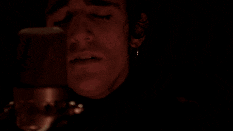 a man is singing into a microphone in a dark room