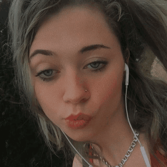 a woman with a nose ring is wearing headphones and a necklace