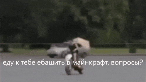 a man is riding a motorcycle down a street with a car behind him .