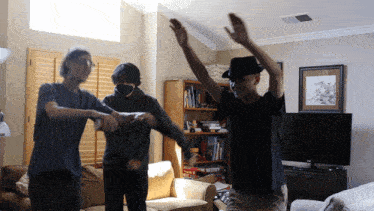 a man wearing a black hat is dancing with two other men