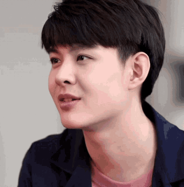 a close up of a young man 's face with a pink shirt on .