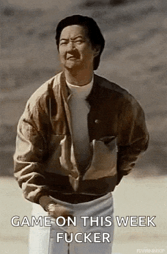 a man in a brown jacket is standing in the dirt with his hands in his pockets and a funny face .