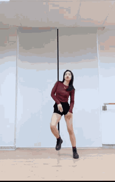 a woman in a red top and black shorts is dancing