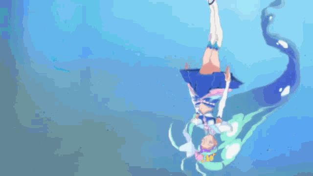 a girl in a blue dress is hanging upside down in a body of water
