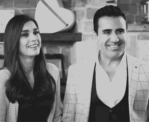 a black and white photo of a man and a woman holding hands and smiling .