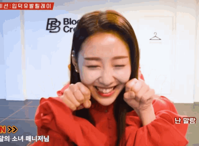 a woman in a red sweater is smiling in front of a sign that says blo