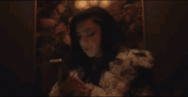 a woman is smoking a cigarette while looking at her phone .