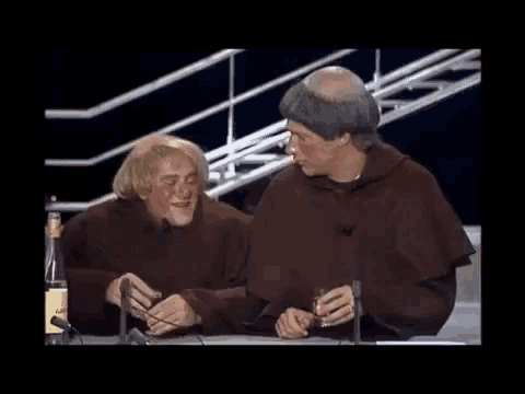 two monks are sitting at a table with microphones .