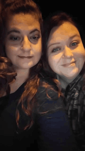 two women are posing for a picture together in the dark