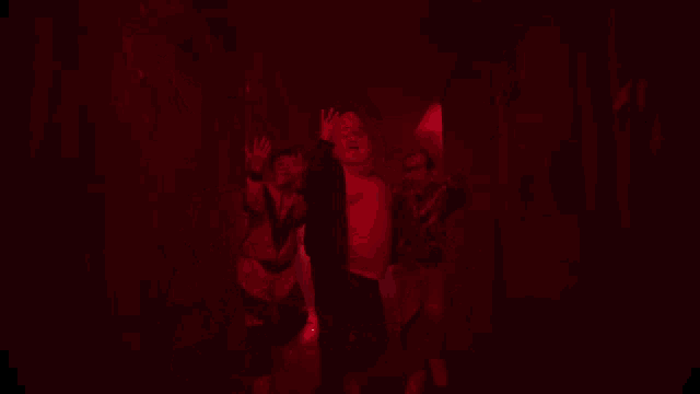 a man in a white shirt is being held up by another man in a red light