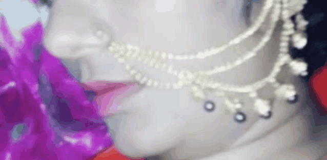 a close up of a woman 's face wearing a nose ring and necklace .