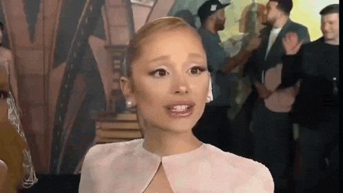 ariana grande is making a funny face while talking to a group of people .