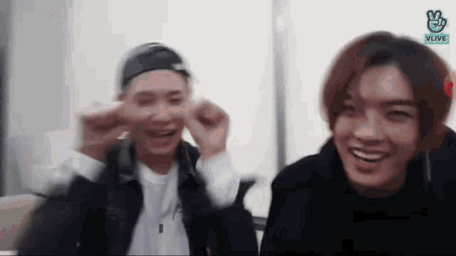 two young men are sitting next to each other making funny faces .