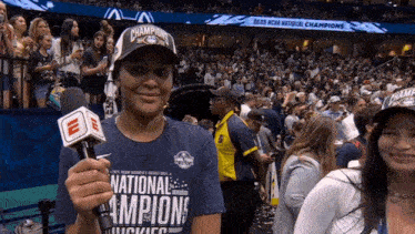 a woman holding a microphone wearing a national champions hat