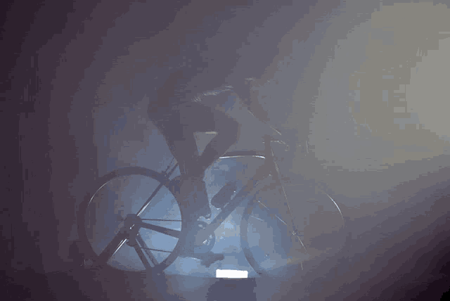 a silhouette of a person riding a bike in a dark room