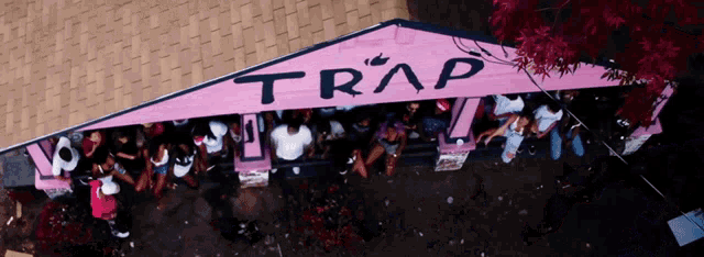 a group of people are gathered under a pink tent that says trap