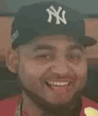 a man wearing a ny yankees hat is eating a french fry .