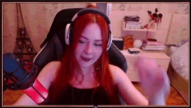 a woman with red hair is wearing headphones while sitting in a chair in front of a microphone .