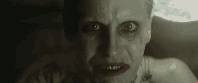 the joker from the movie suicide squad is looking at the camera with a serious look on his face .
