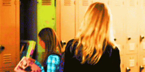 a woman carrying a pink purse with the letter f on it walks in a locker room