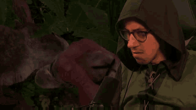 a man wearing glasses and a hooded jacket is making a face .