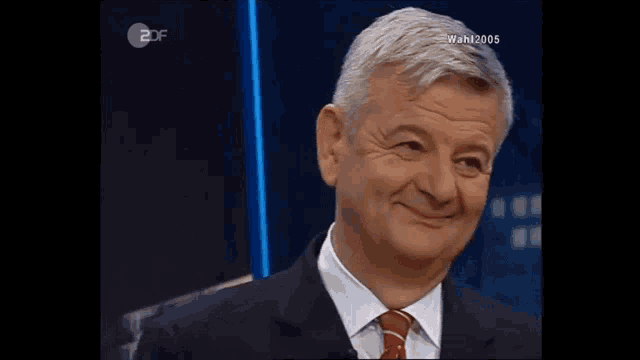a man in a suit and tie is smiling in front of a 2df screen