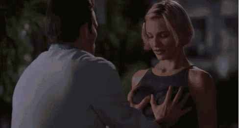a man is touching a woman 's breast while standing next to her .