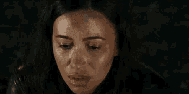 a close up of a woman 's face with water coming out of her hair in a dark room .