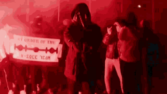 a group of people are standing in a dark room holding a banner that says `` by order of the k-rock team '' .