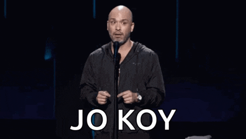 a bald man is standing in front of a microphone with the words `` jo koy '' written on it .