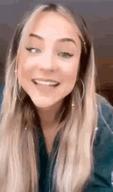 a close up of a woman wearing hoop earrings and a blue shirt .