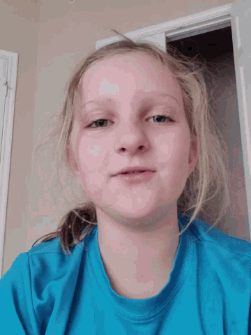a young girl wearing a blue shirt looks down at the camera
